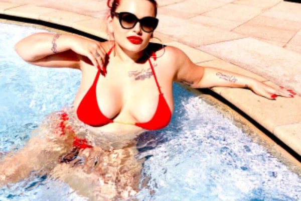 Die Geldherrin liegt in einem roten Bikini und mit großer schwarzer Sonnenbrille lasziv in einem Pool.